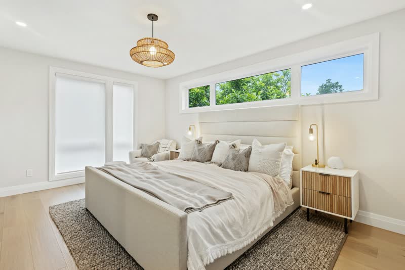 A bright bedroom with a pendant lamp and a row of transom windows