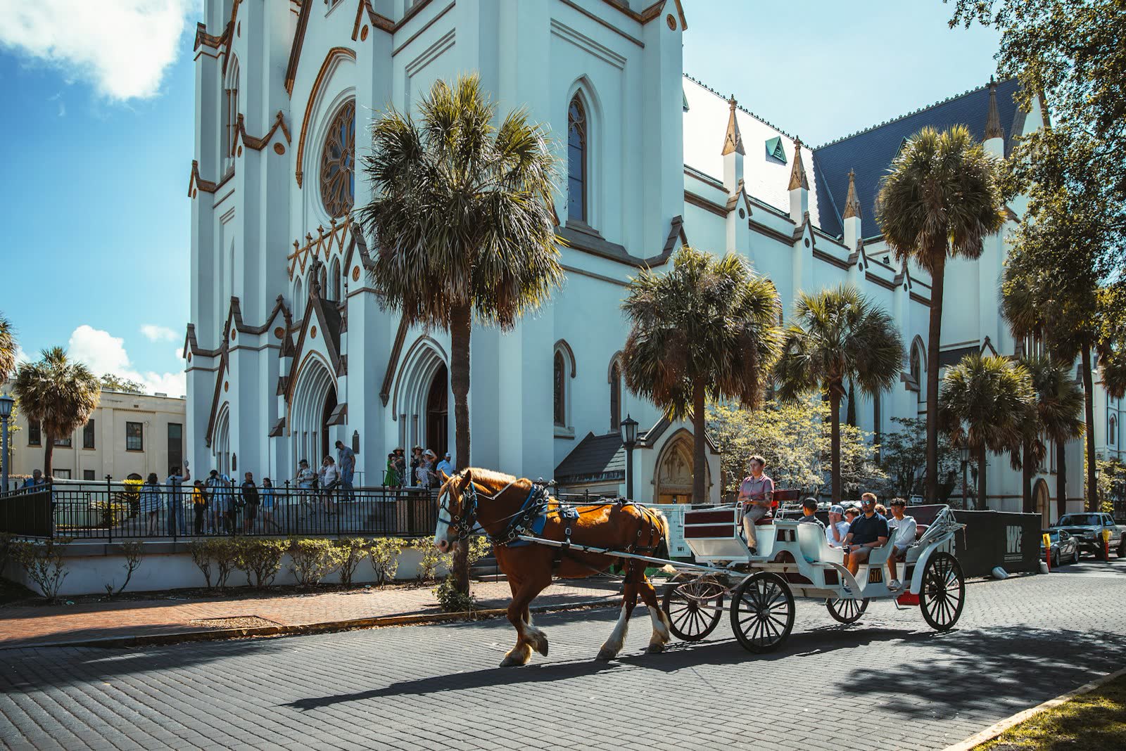 A horse-drawn carriage passing the cathedral on a sunny Savannah street