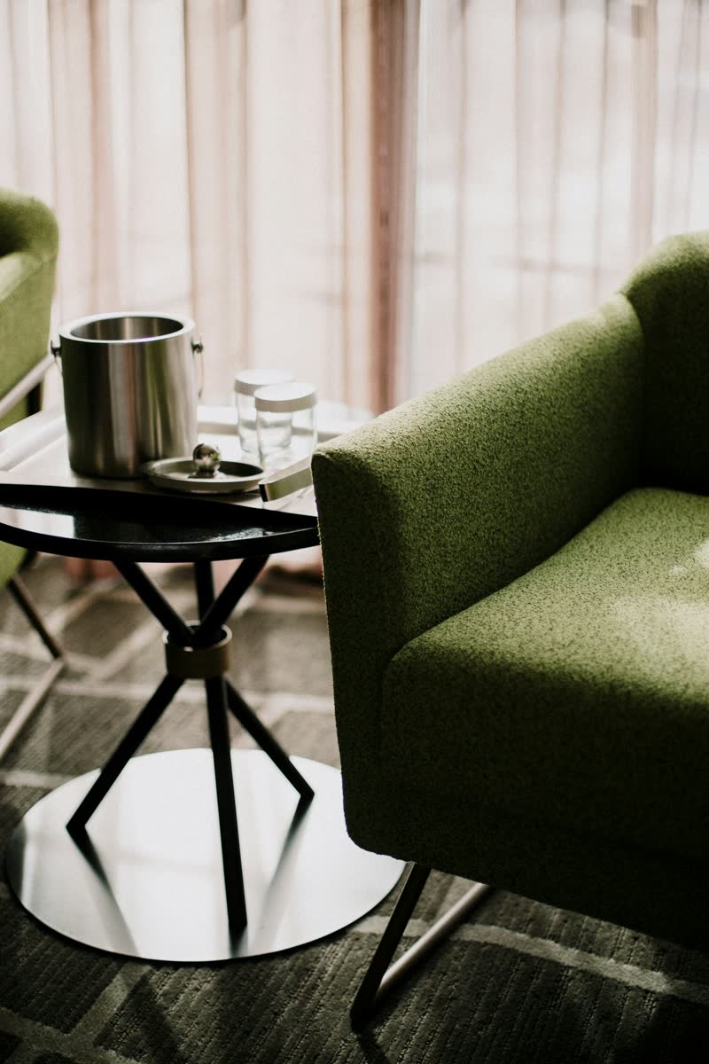 A green armchair beside a small black table with an ice bucket and glasses