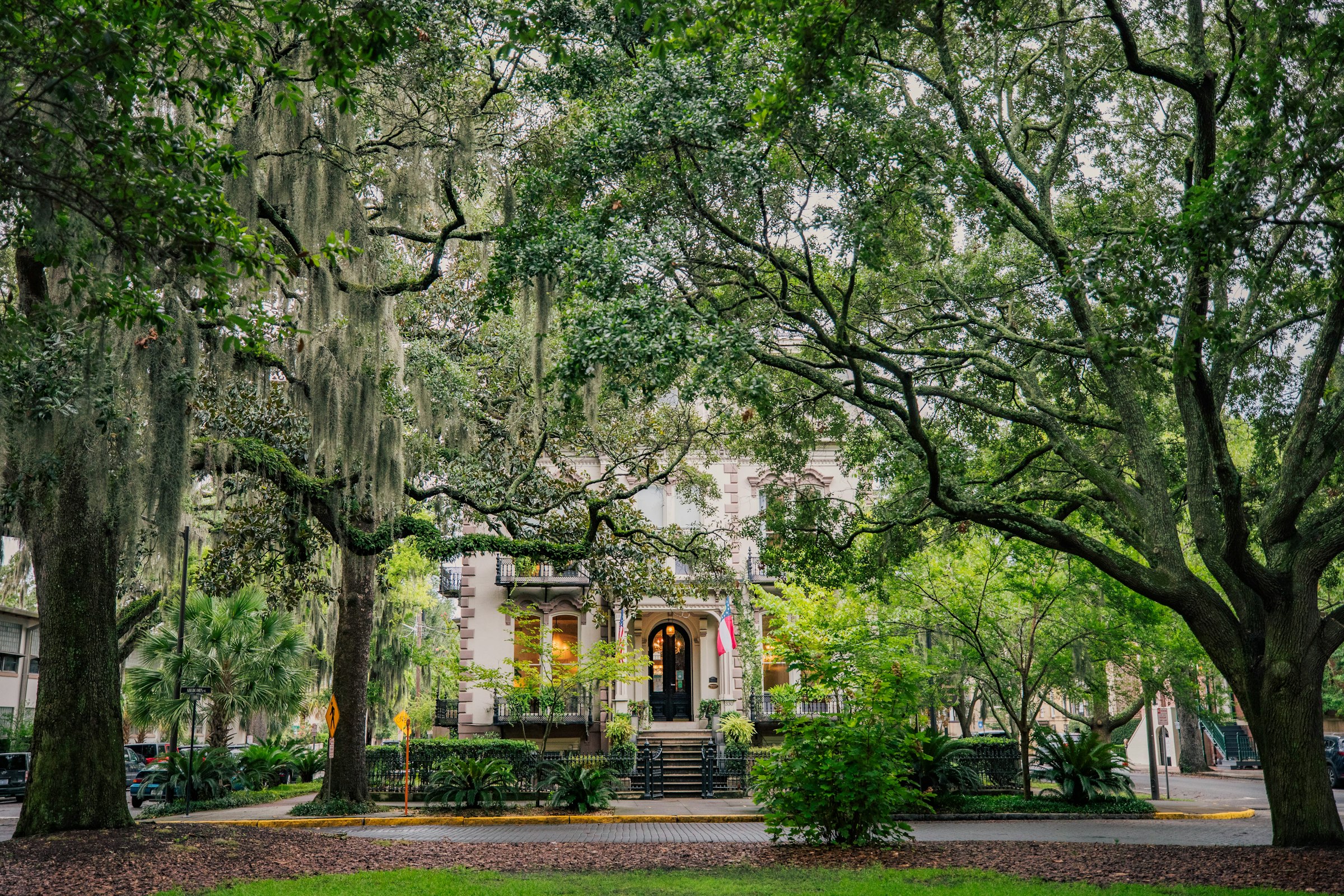A grand Savannah house seen through live oaks draped in Spanish moss